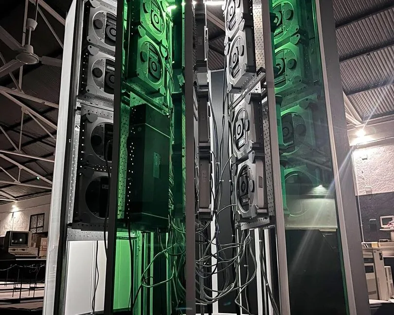 A vertical photo showing the size of the Cray-1 replica project. A large C-shaped tower stands lit up with green accent lighting.